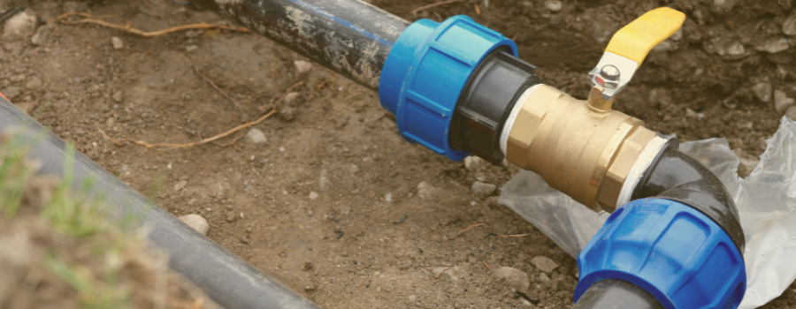 Underground water pipes with a yellow valve handle.